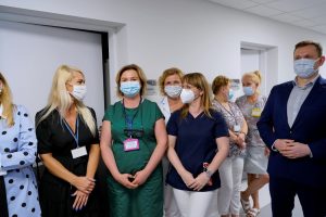 osoby ubrane w ubrania medyczne i wizytowe oraz maseczki ochronne na twarzy na korytarzu koloru białego oddziału ZOL szpitala.