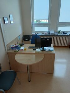 pomieszczenie z biurkiem koloru brązowego ze sprzętem komputerowym i niebieskim fotelem obrotowym