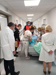 Zol na korytarzu koloru białego 4 osoby mające na twarzy maseczki ochronne przenoszą pierwszego pacjenat ZOL