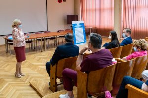 Sala konferencyjna. Przemawia naczelna pielęgniarka do osób przebywajacych podczas wreczania certyfikatu dla szpitala