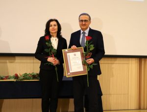 dwie osoby ubrane w ubrania wizytwie dyrektor w ręce trzyma dyplom