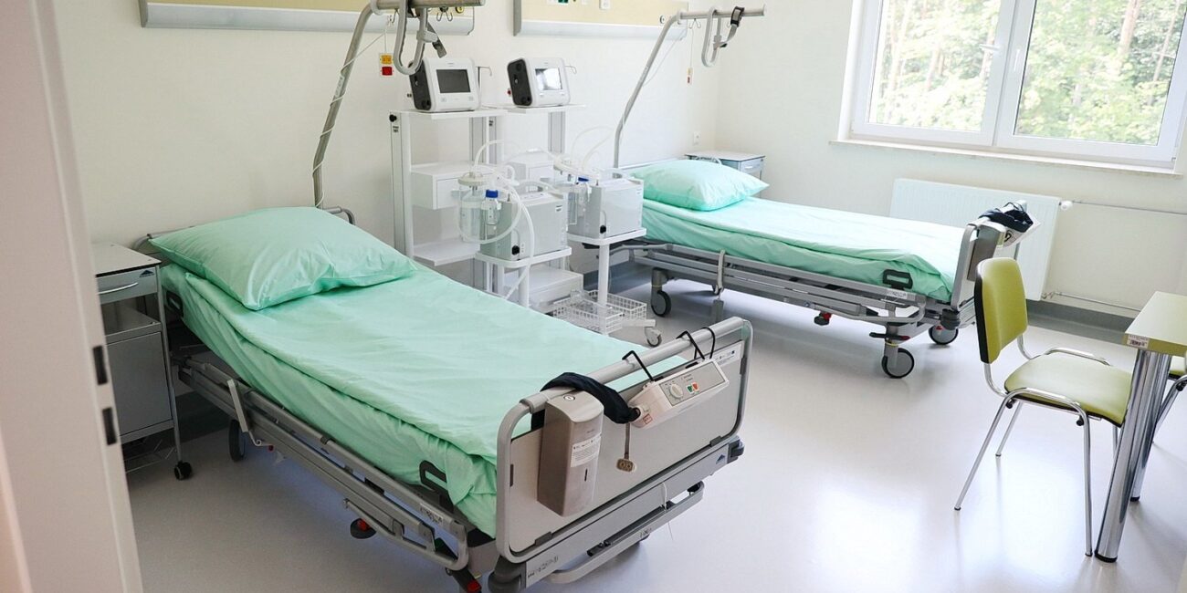 Zdjęcie przedstawia wyposażenie nowej sali. W sali znajdują się dwa łóżka, sprzęt medyczny i stolik