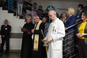 Biskup, wraz z tłumem osób na szpitalnym korytarzu