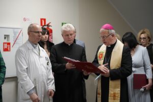 Grupa osób, z biskupem na czele czytającym tekst z księgi.