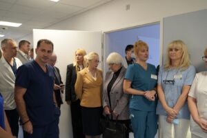 Grupa osób stojąca na korytarzu i odwiedzająca nowe sale szpitalne.