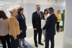Fotografia przedstawia uśmiechniętą grupę osób, stojącą na korytarzu szpitalnym